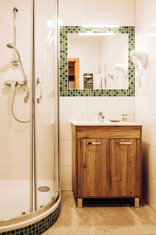 Un baño con ducha de vidrio, tocador de madera con espejo y salpicadero de azulejos.
