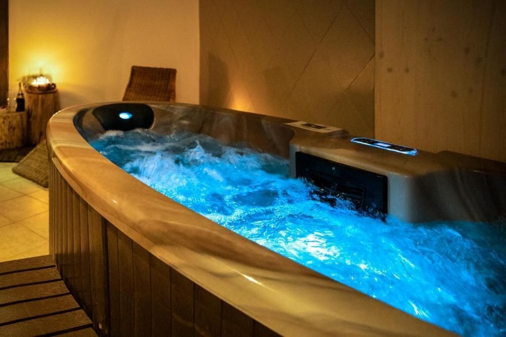 A hot tub with a digital control panel and a wooden bench beside it.