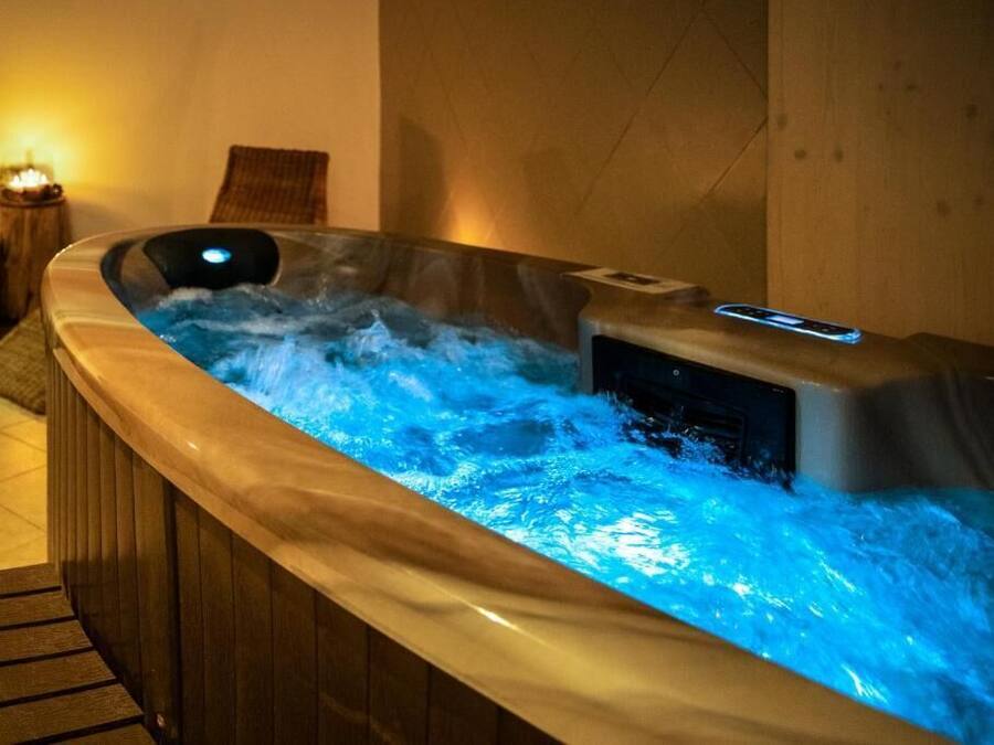 A hot tub with a digital control panel and a wooden bench beside it.