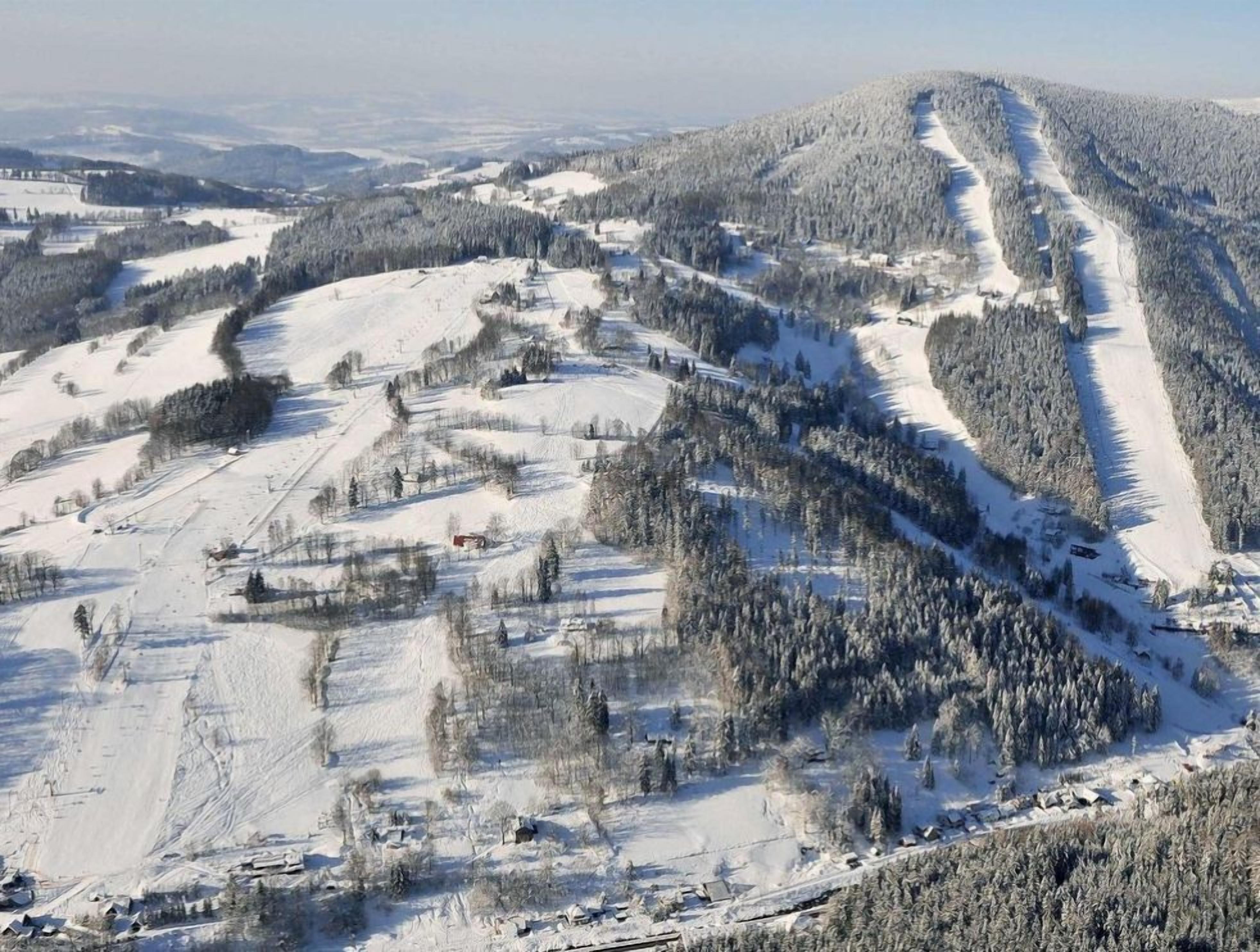 Un paisaje montañoso cubierto de nieve con senderos de esquí.