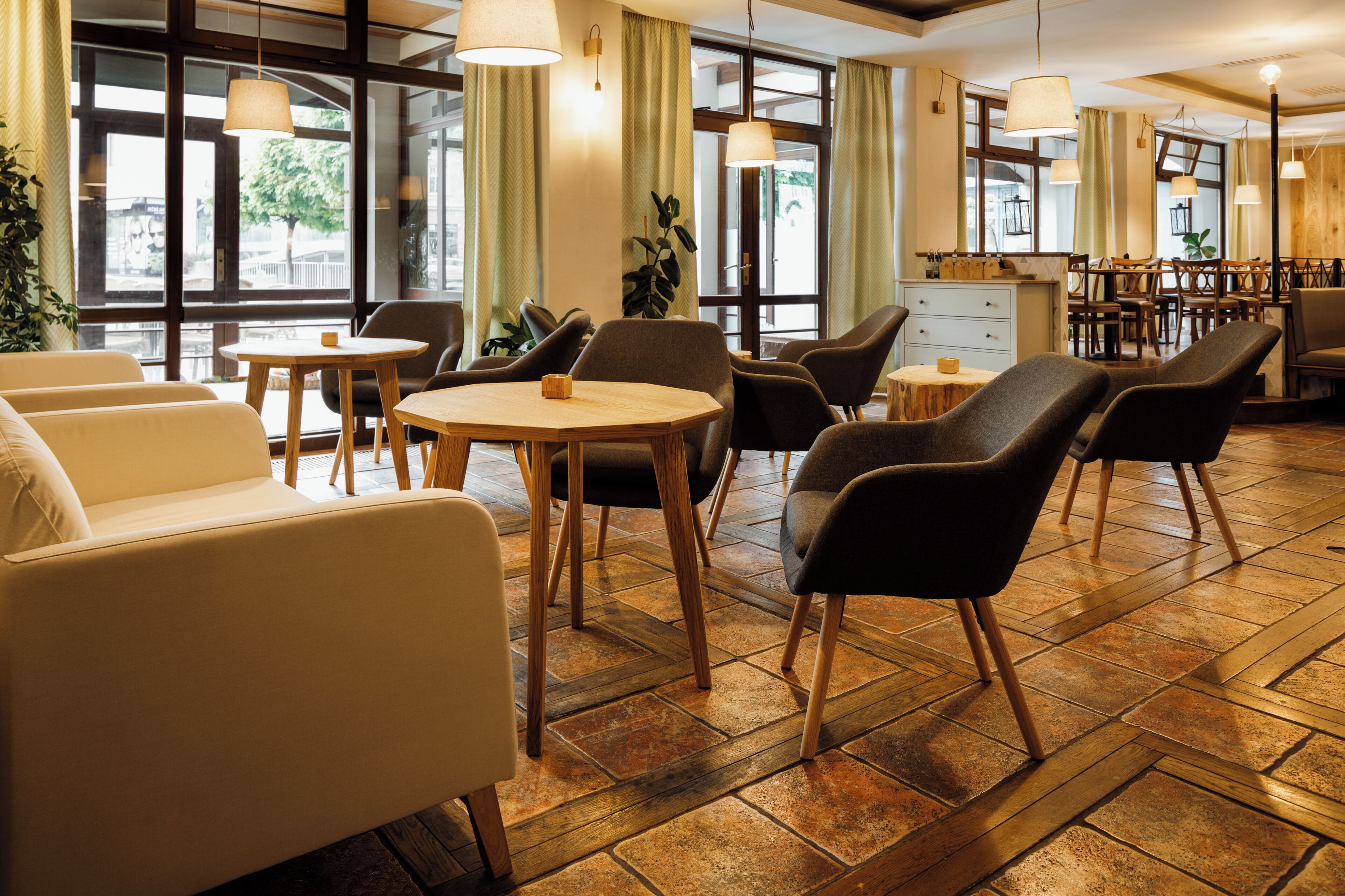 Una moderna hall d'albergo con aree salotto, una reception e ampie finestre.