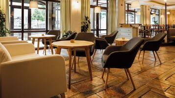 A modern hotel lobby with seating areas, a reception desk, and large windows.