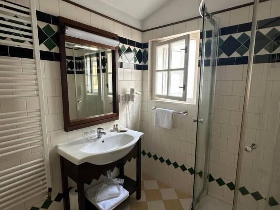 A bathroom with a sink, mirror, window, and shower.