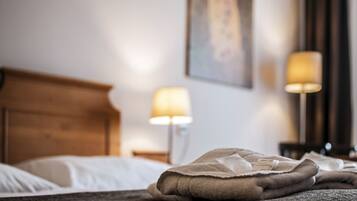 A neatly made bed with a folded blanket and pillows, two bedside lamps, and a painting on the wall.