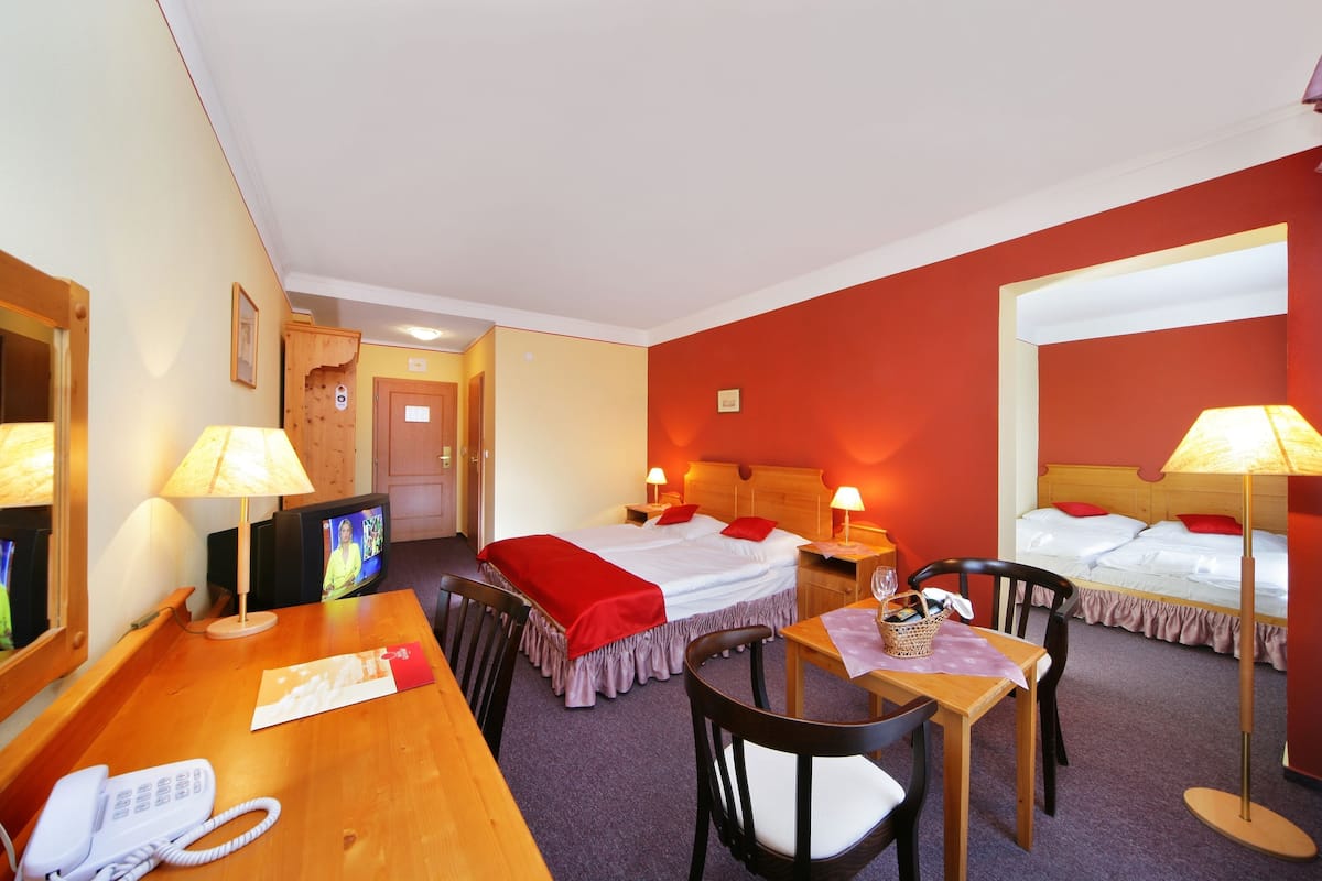 A hotel room with two beds, a desk with a phone, a TV, and two lamps.