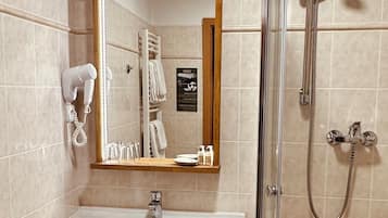 A bathroom with a sink, mirror, shower, and towel rack.