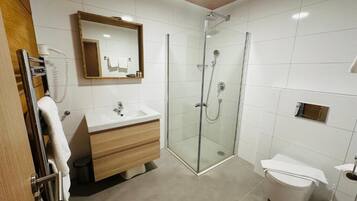 Une salle de bain moderne avec une douche à parois de verre, un meuble-lavabo en bois et un lavabo blanc.