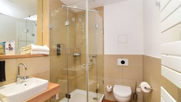 Une salle de bain moderne dotée d’une douche à parois de verre, d’un lavabo et de toilettes.