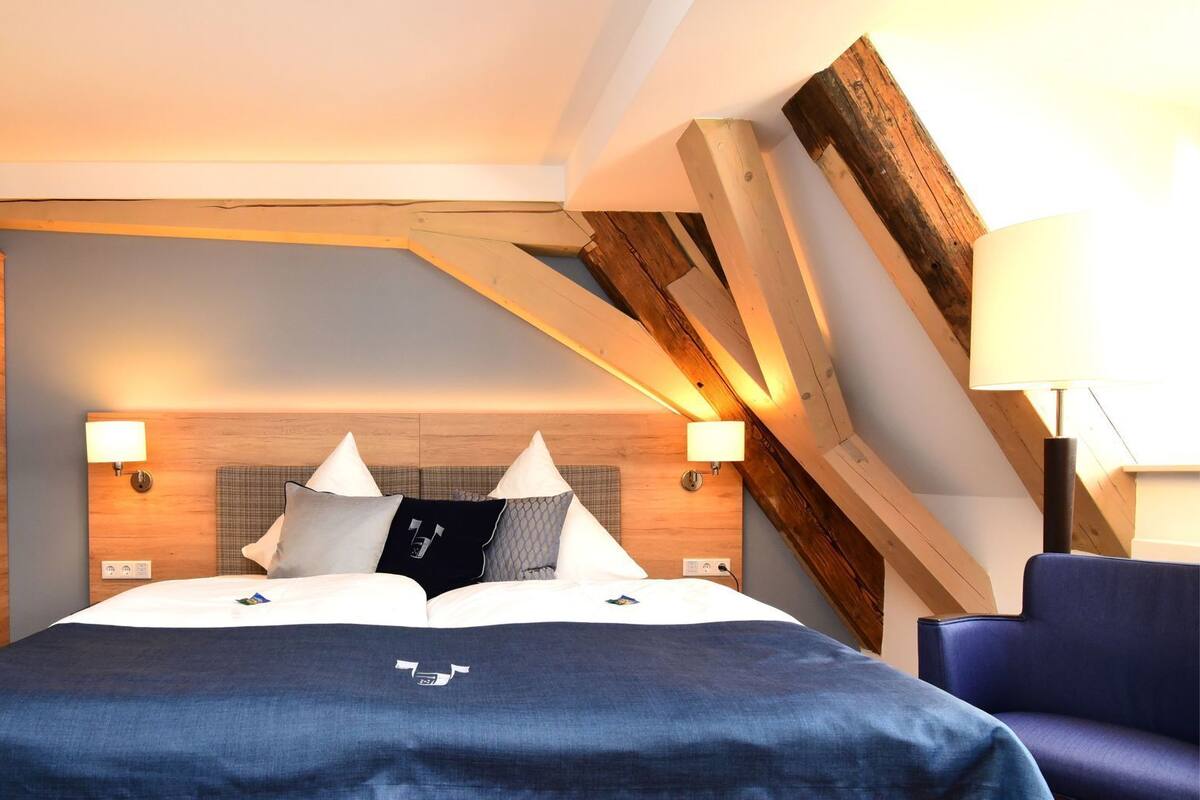 A modern hotel room with a large bed, wooden headboard, and two bedside lamps.