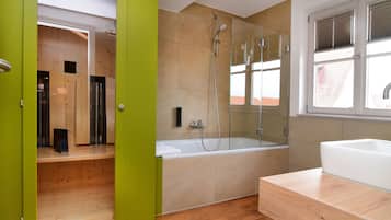 Un baño moderno con cabina de ducha acristalada, tocador de madera y un amplio ventanal que proporciona luz natural.