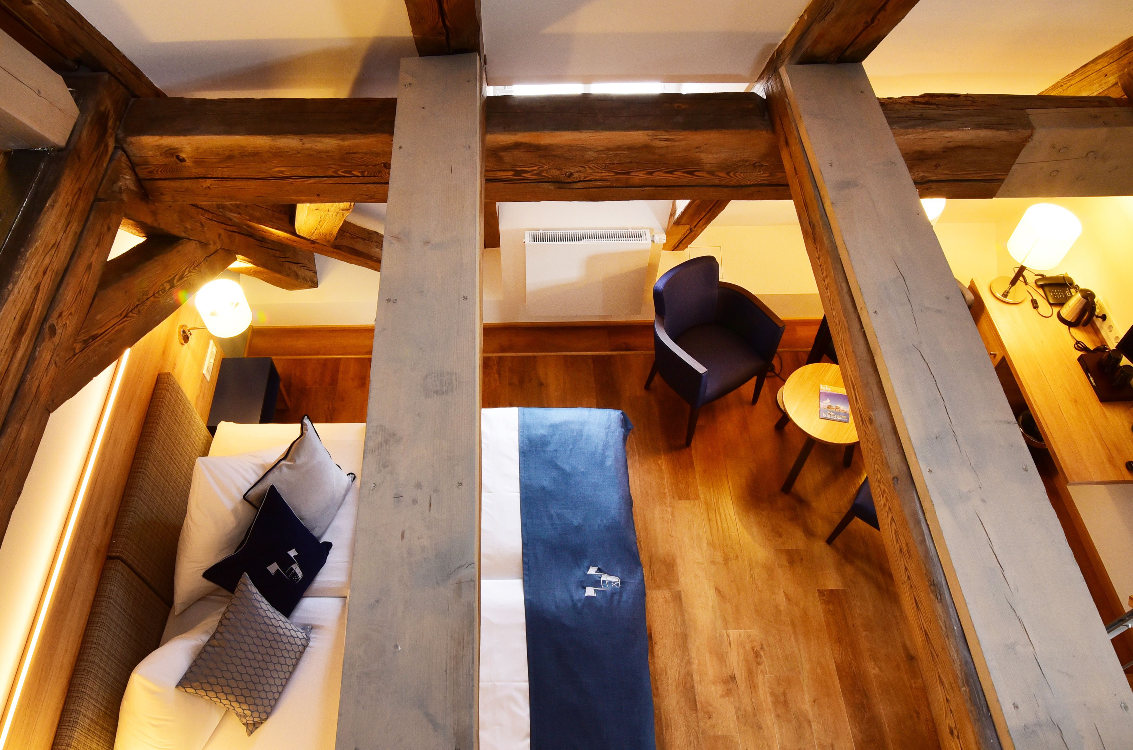Una habitación acogedora con techo de madera, un sofá con cojines, una mesita redonda y una silla.
