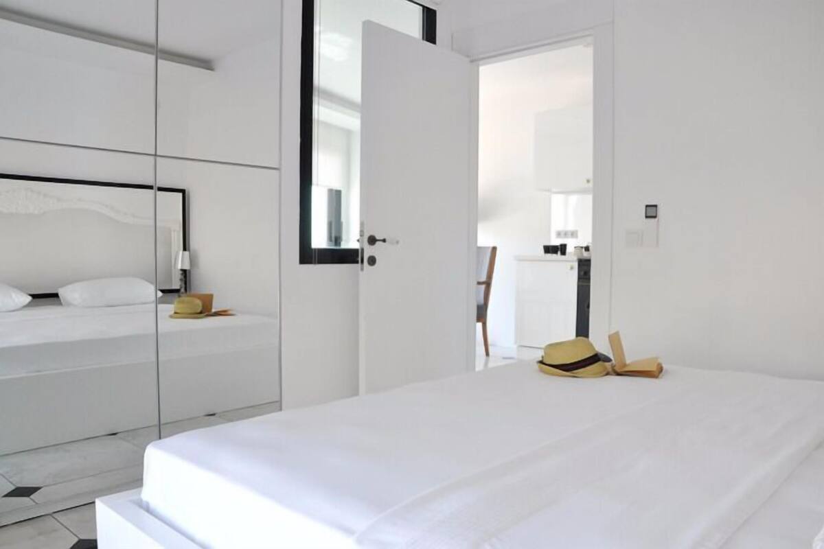 Ein schlicht eingerichtetes Hotelzimmer mit einem großen Bett, einem Kleiderschrank und einem Spiegel.
