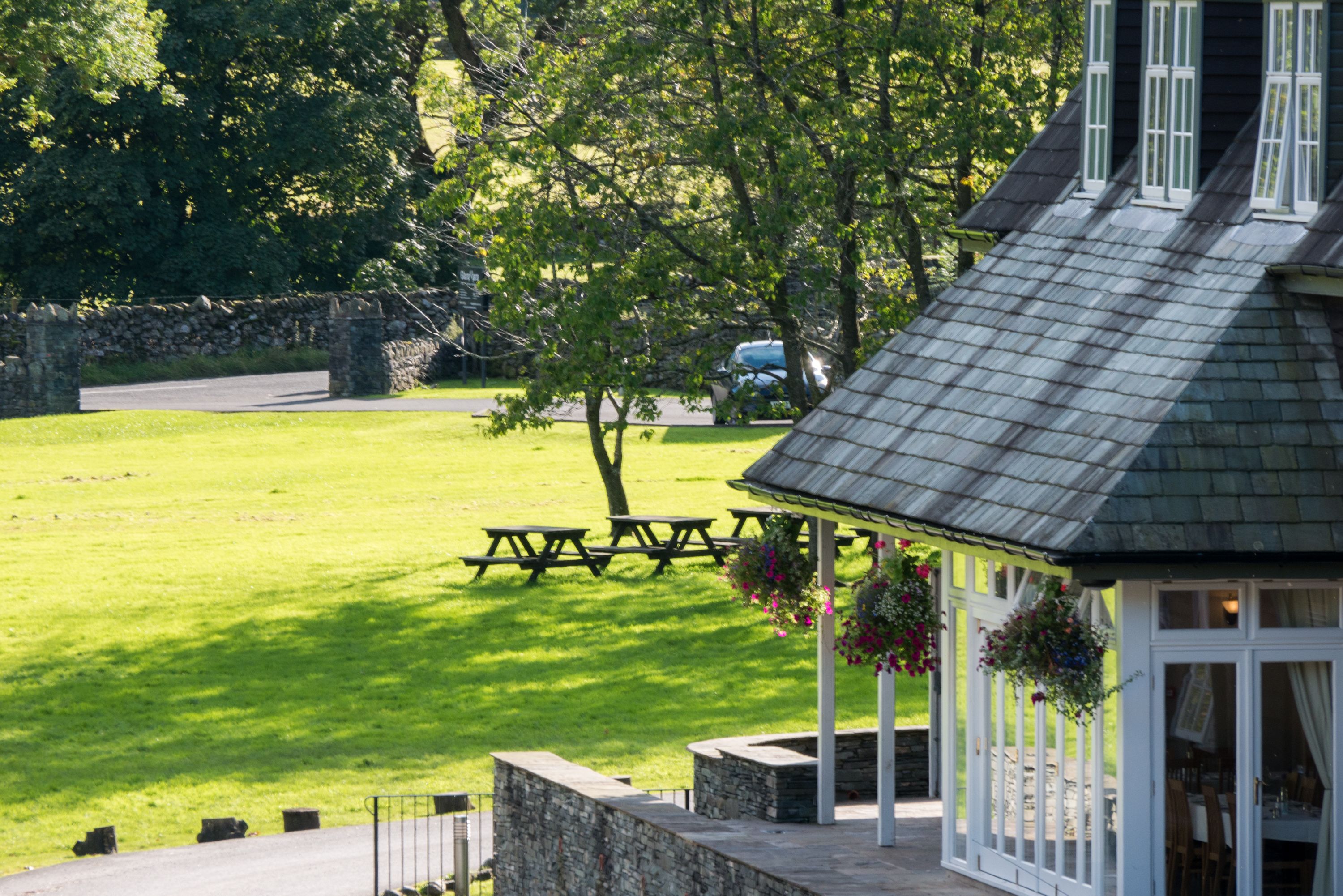 A gazebo with stone walls, a picnic table, and hanging flower baskets.