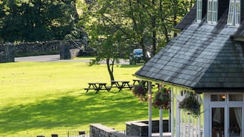 A gazebo with stone walls, a picnic table, and hanging flower baskets.
