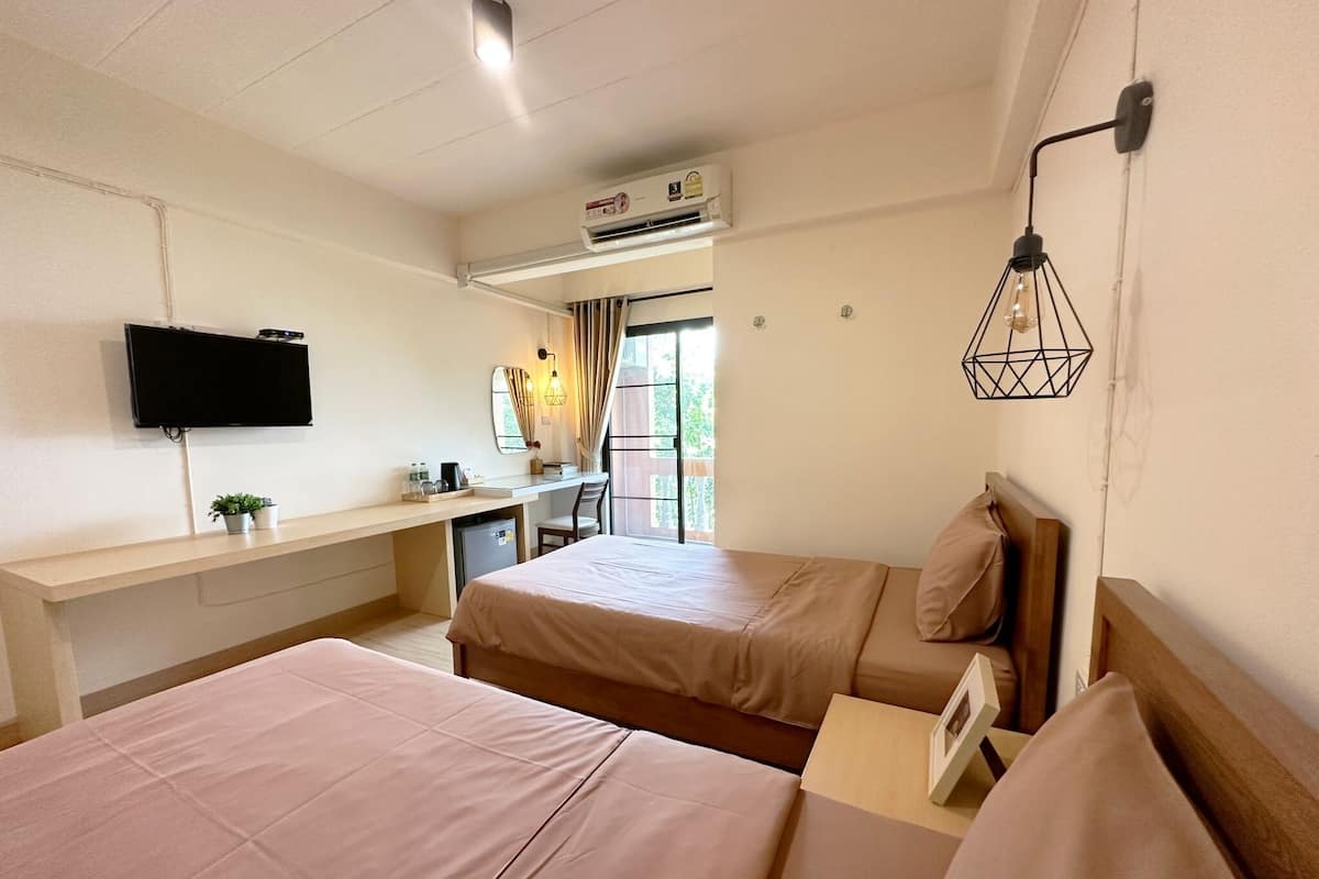 Habitación de hotel con dos camas, un escritorio, un televisor y un equipo de aire acondicionado.