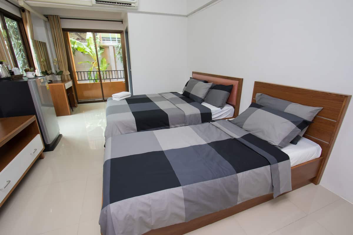 Habitación de hotel con dos camas, un escritorio, una silla y una ventana con cortinas.