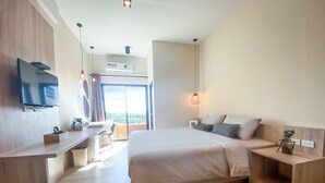 A modern hotel room with a large bed, a desk with a chair, a TV mounted on the wall, and a balcony with a view. - I-Home Residence and Hotel (Pluak Daeng)
