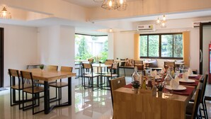A spacious dining area with multiple tables and chairs, large windows, and pendant lighting. - I-Home Residence and Hotel (Pluak Daeng)