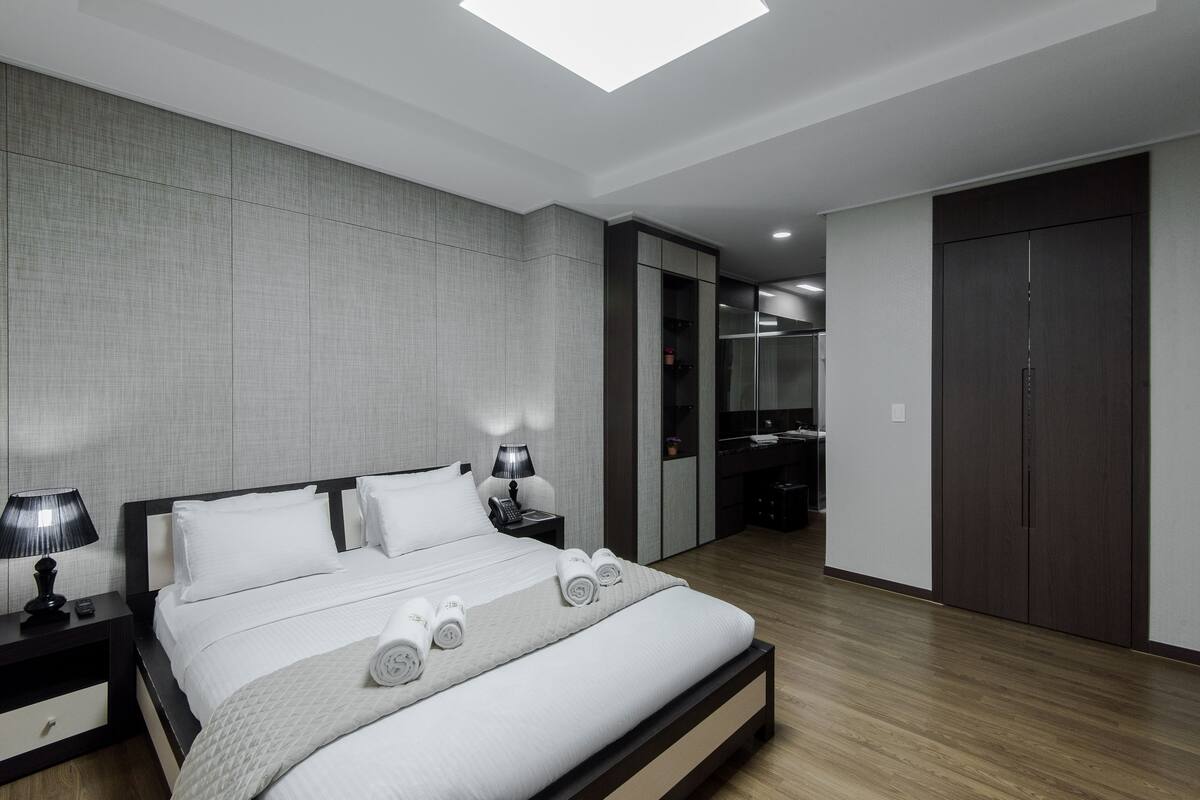 A modern bedroom with a large bed, bedside tables, a wardrobe, and a walk-in closet.