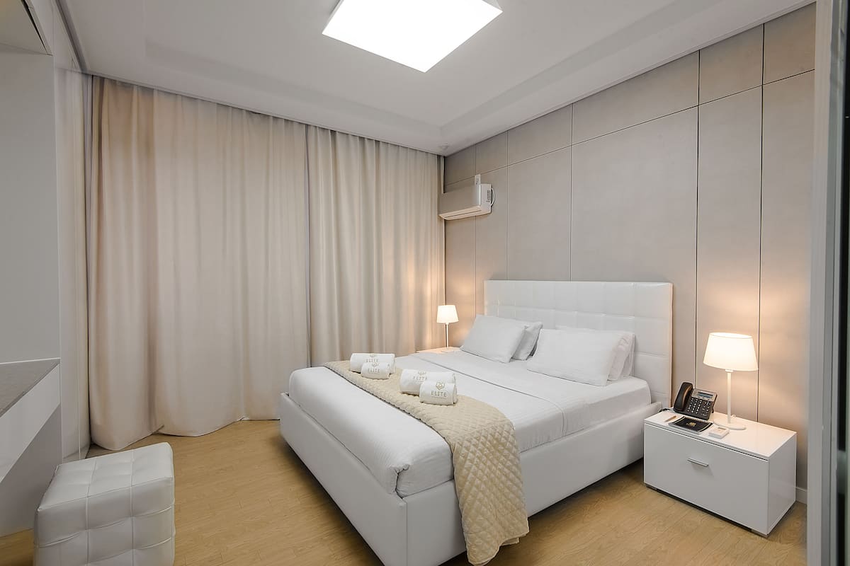 A modern bedroom with a large bed, bedside tables, a nightstand, and a ceiling light.