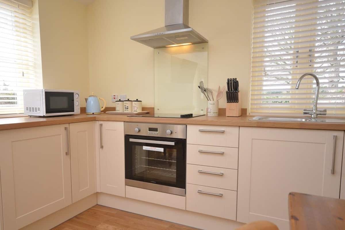 A compact kitchen with a microwave, oven, and sink.