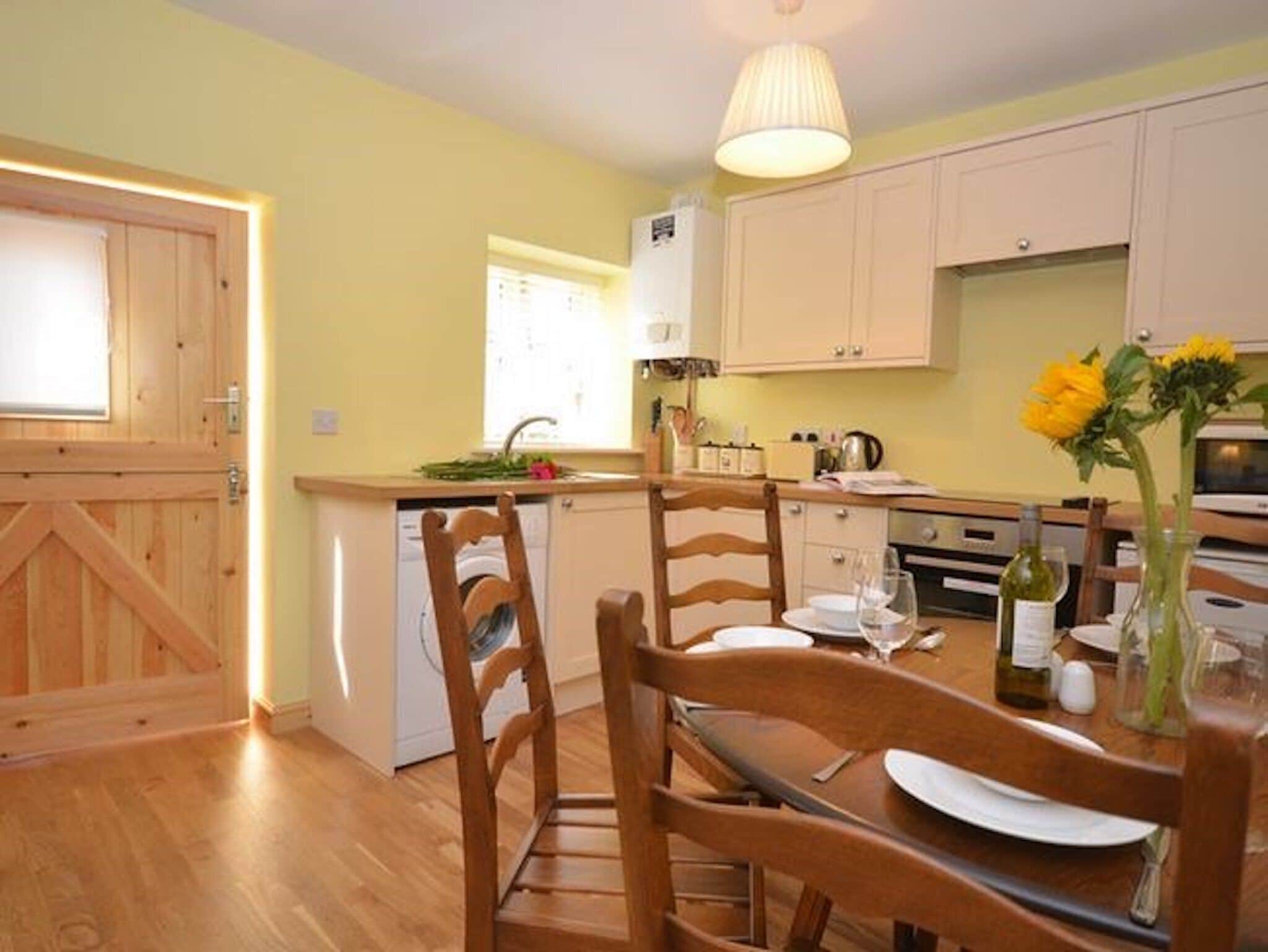 A kitchen with wooden cabinets, a dining table with chairs, and a vase with flowers.