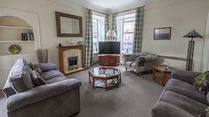 A living room with a fireplace, a television, and two sofas. - 1 Varis Apartments (Forres)