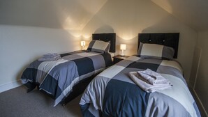 A hotel room with two beds, each with a headboard, bedside lamps, and towels. - 1 Varis Apartments (Forres)