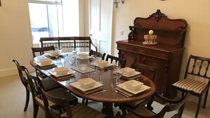 A dining room with a round table set for six, surrounded by wooden chairs with cushioned seats. - 1 Varis Apartments (Forres)