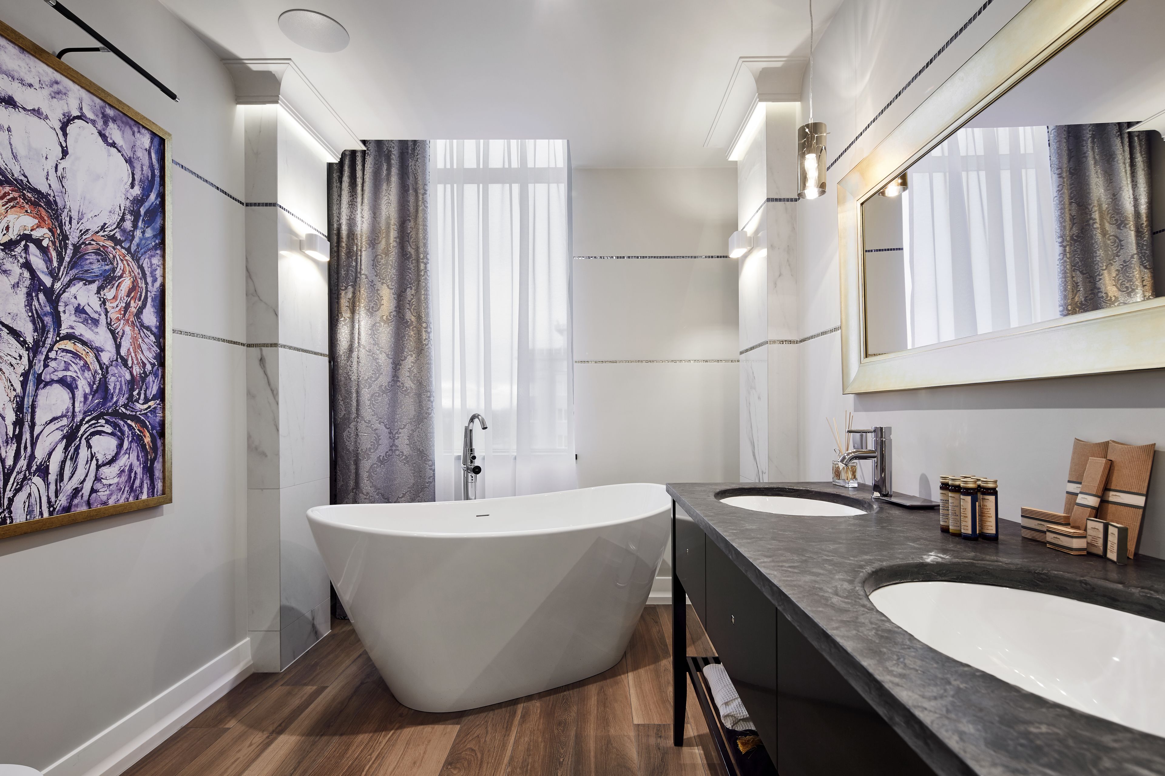 Un baño moderno con una bañera independiente, dos lavamanos y un espejo grande.