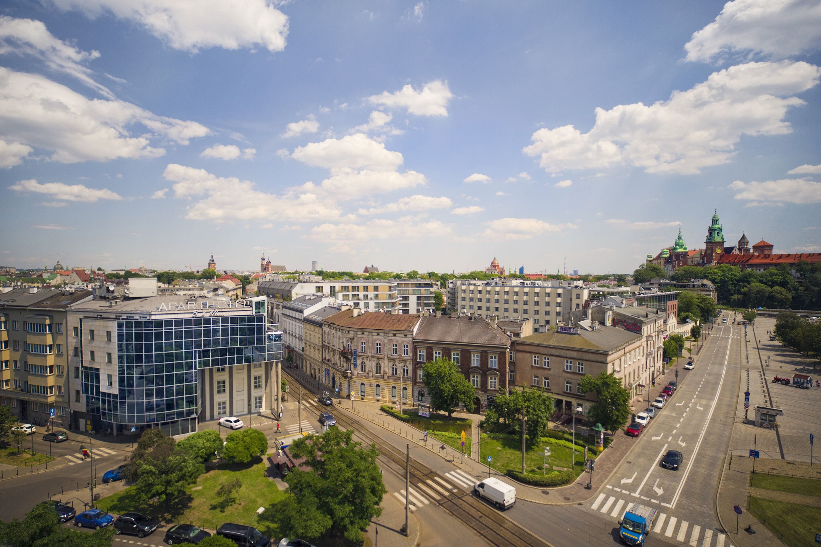 Un paysage urbain avec des bâtiments modernes et historiques, une large rue et une ligne de tramway.