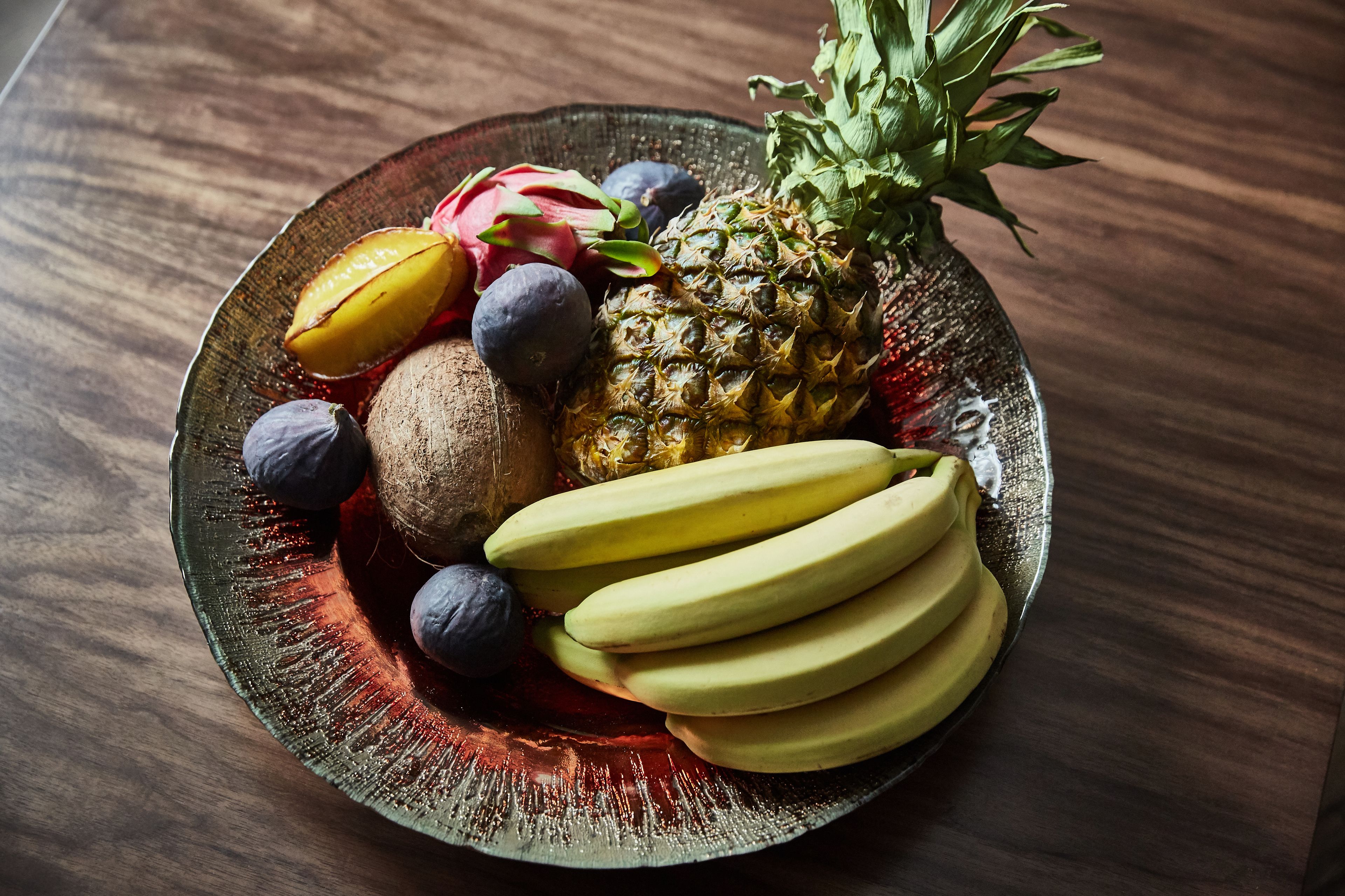 Ein Teller mit Obst, darunter Ananas, Drachenfrucht, Kiwi und Bananen.