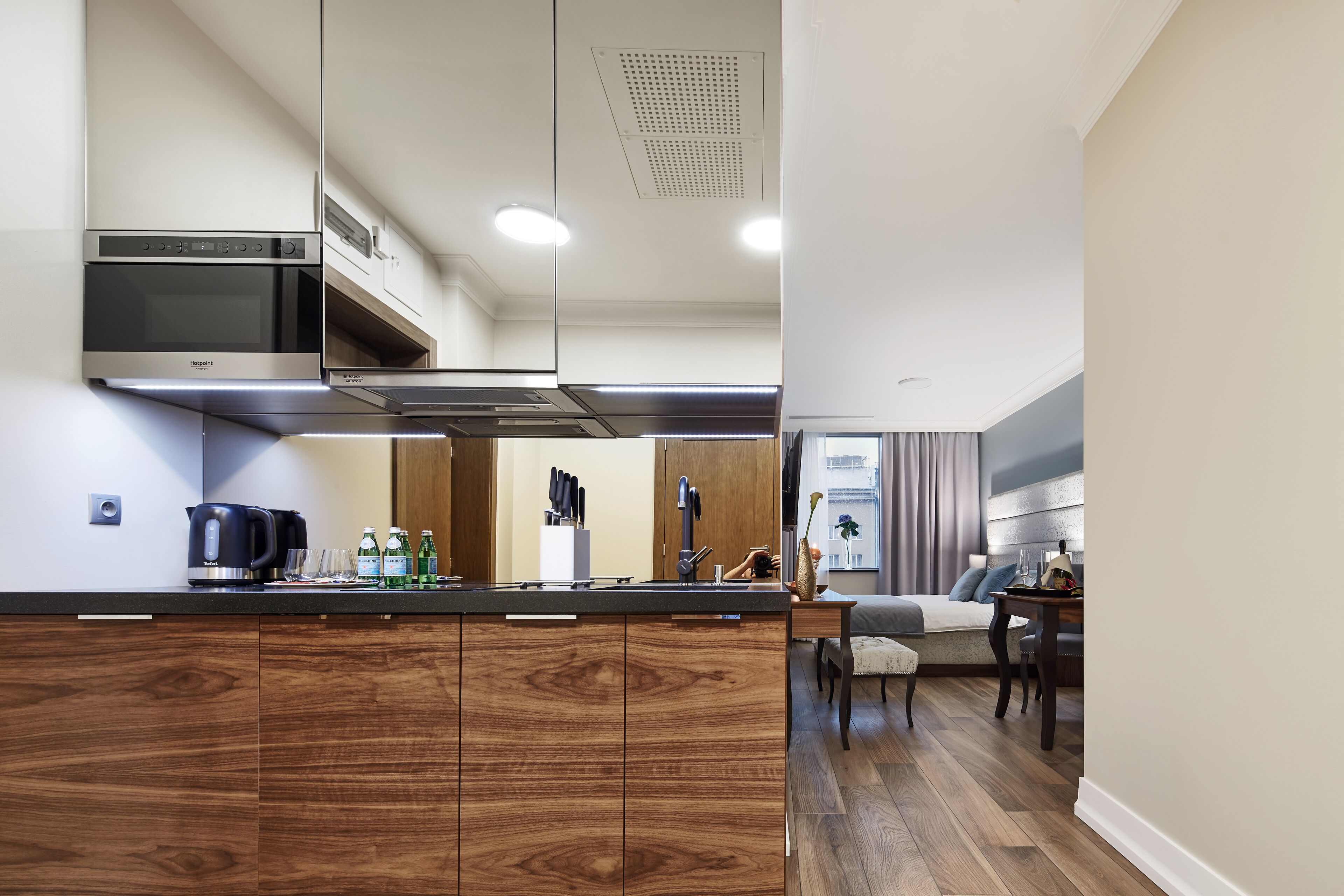 A modern kitchen with wooden cabinets, a built-in oven, and a coffee maker.