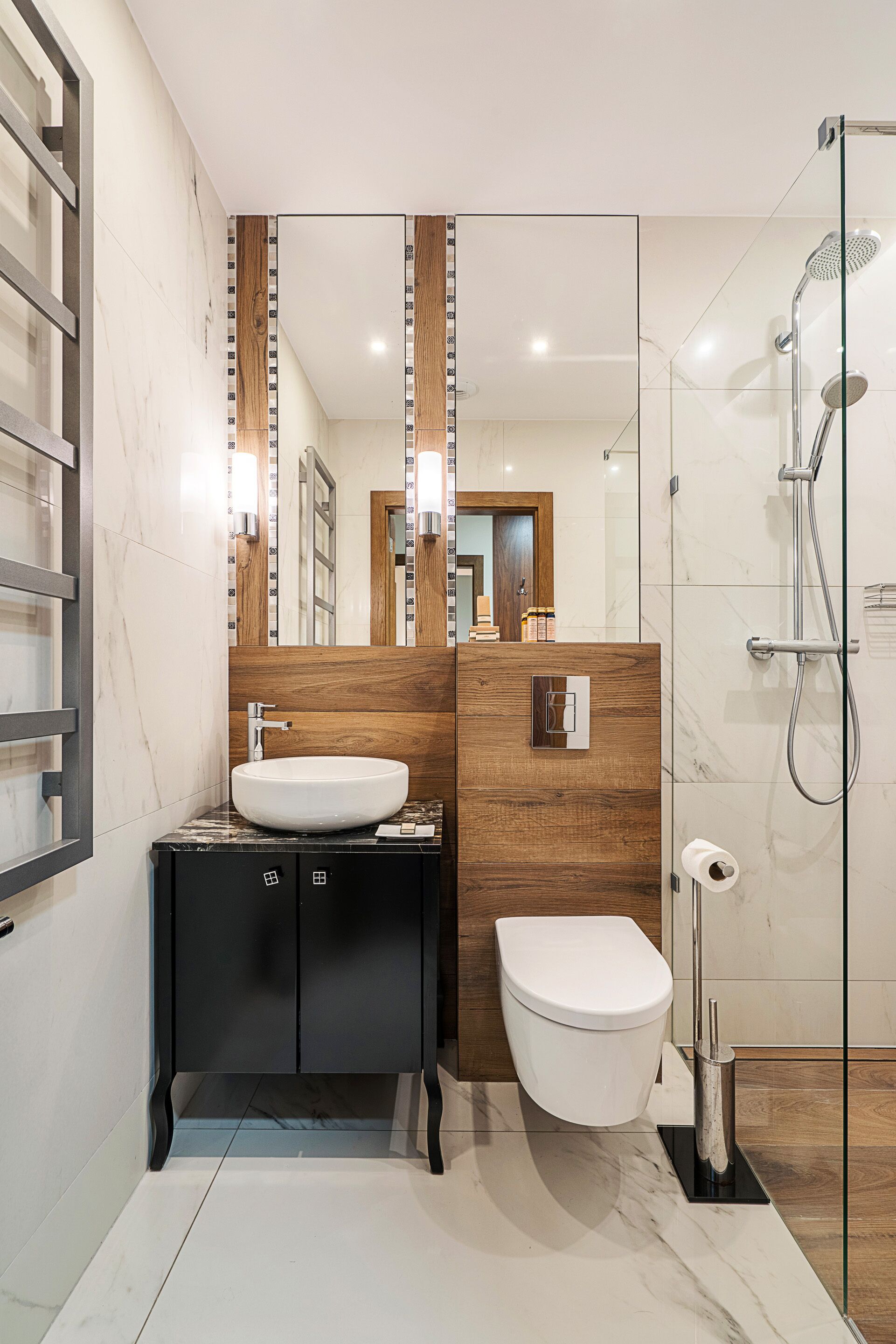 A modern bathroom with a large mirror, a sink, a toilet, and a glass-enclosed shower area.