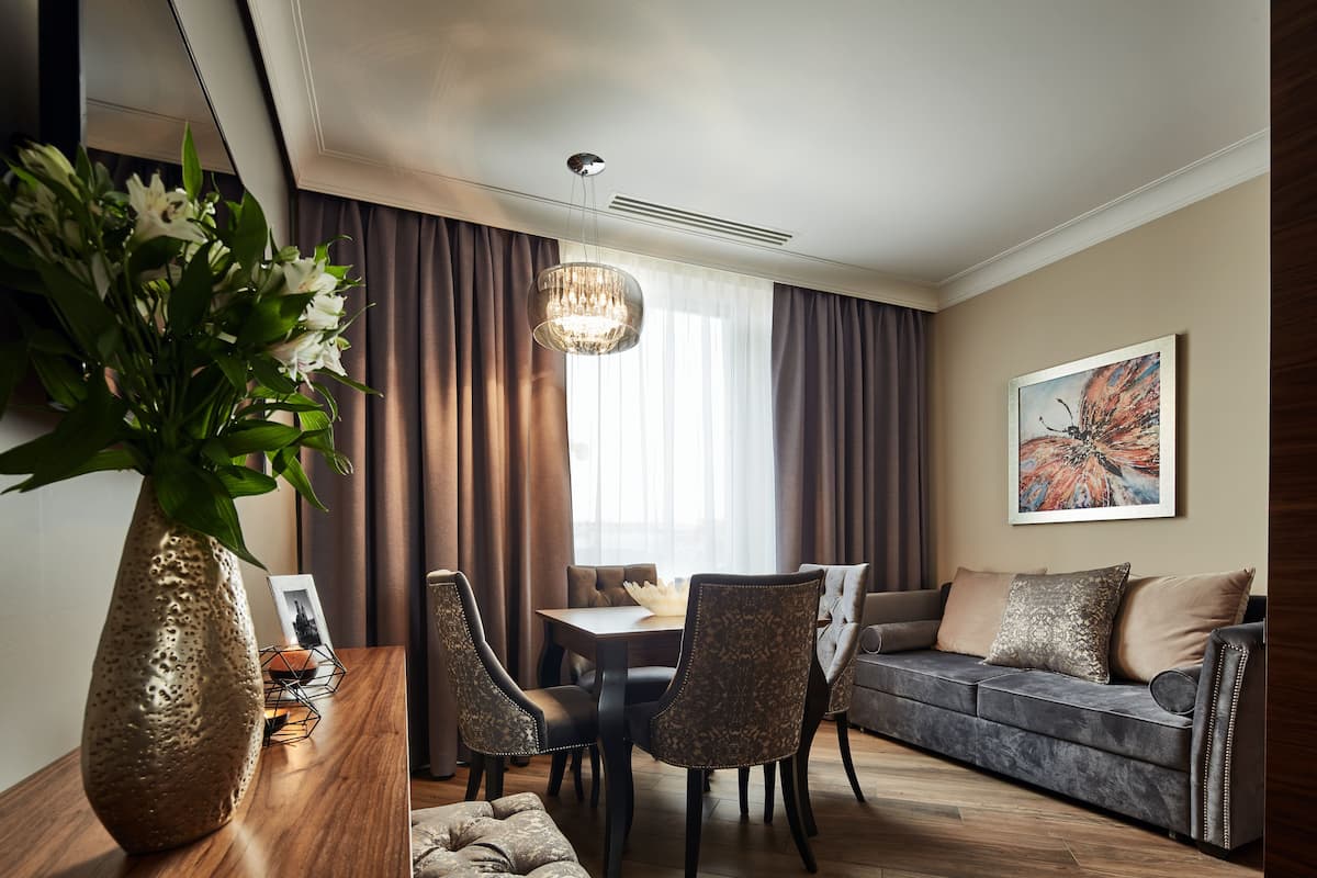 A modern living room with a dining table, sofa, and chairs. There is a vase with flowers on a wooden table.