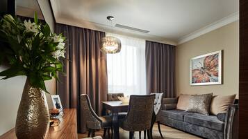 A modern living room with a dining table, sofa, and chairs. There is a vase with flowers on a wooden table.
