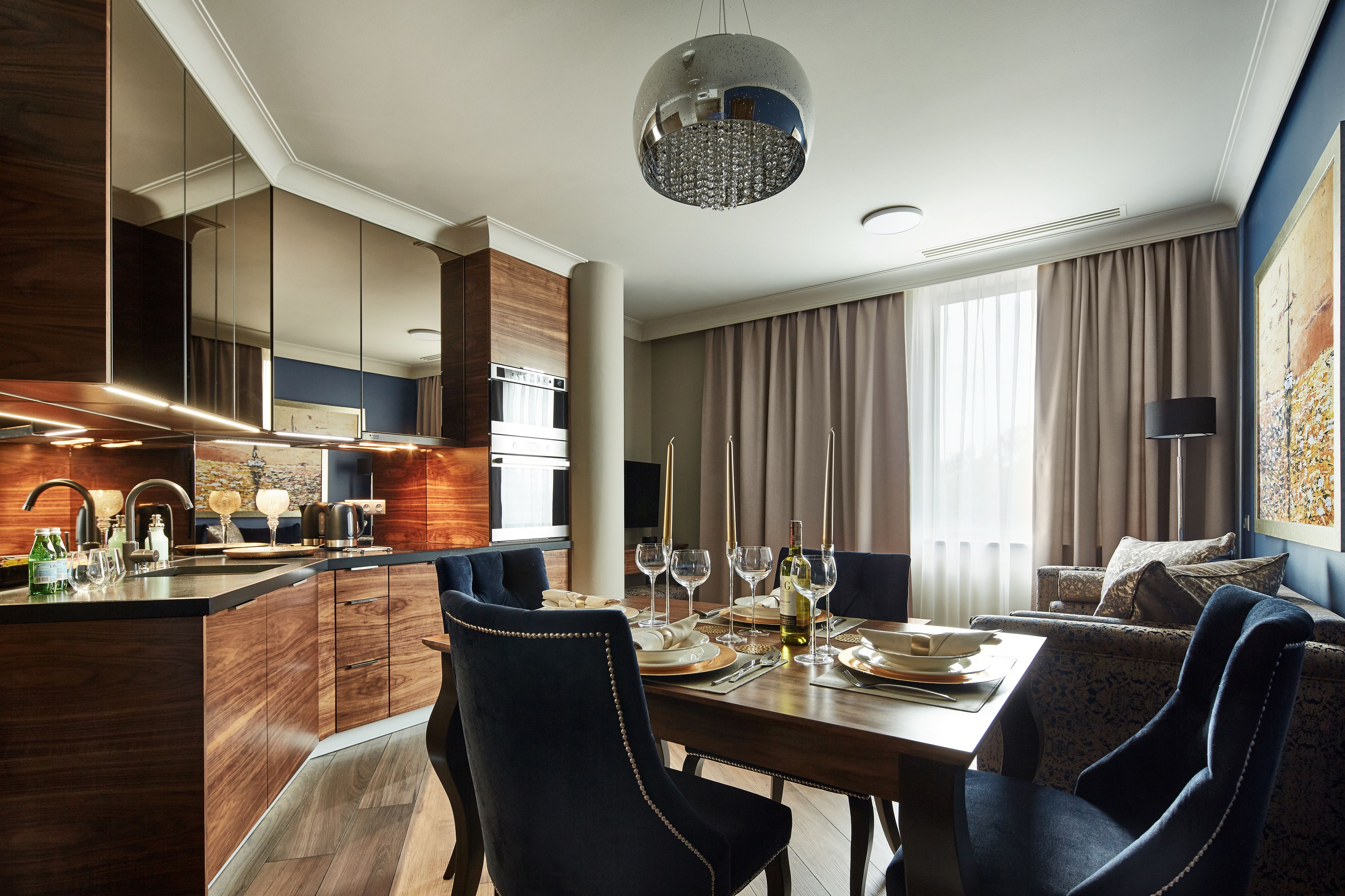 A modern hotel room with a dining area, a kitchen, and a living space.