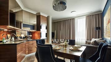 A modern hotel room with a dining area, a kitchen, and a living space.