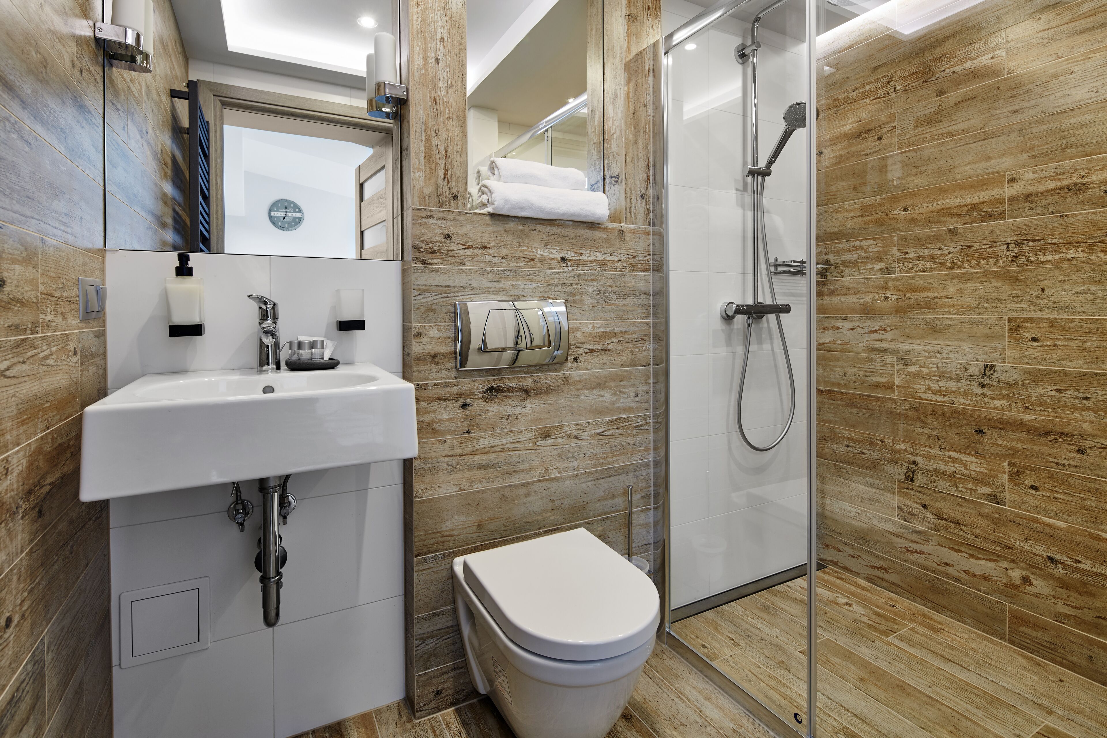 Un baño moderno con lavamanos blanco, inodoro y ducha con mampara de vidrio.