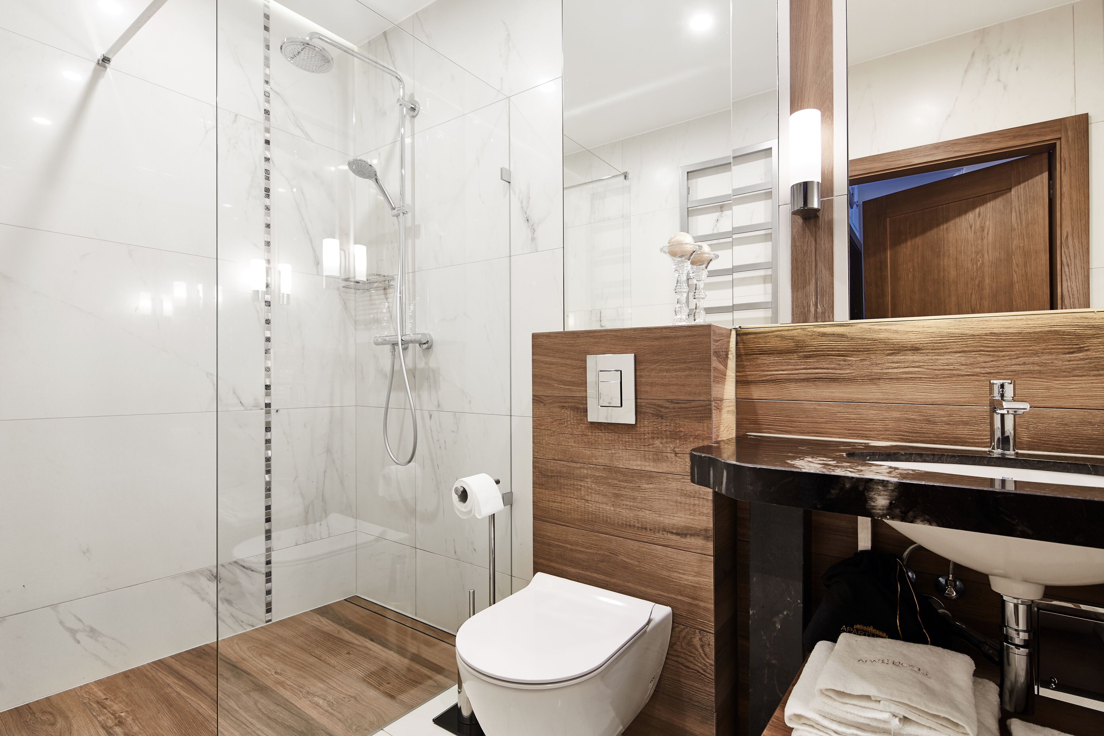 Un baño moderno con ducha de vidrio, tocador de madera con lavabo e inodoro.