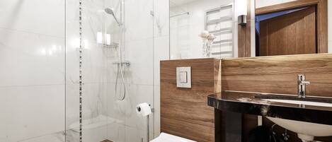 Un baño moderno con ducha de vidrio, tocador de madera con lavabo e inodoro.