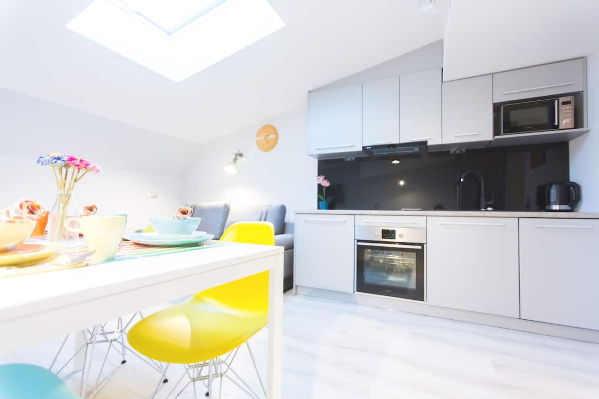 A modern kitchen with white cabinets, a black microwave, and a built-in oven.