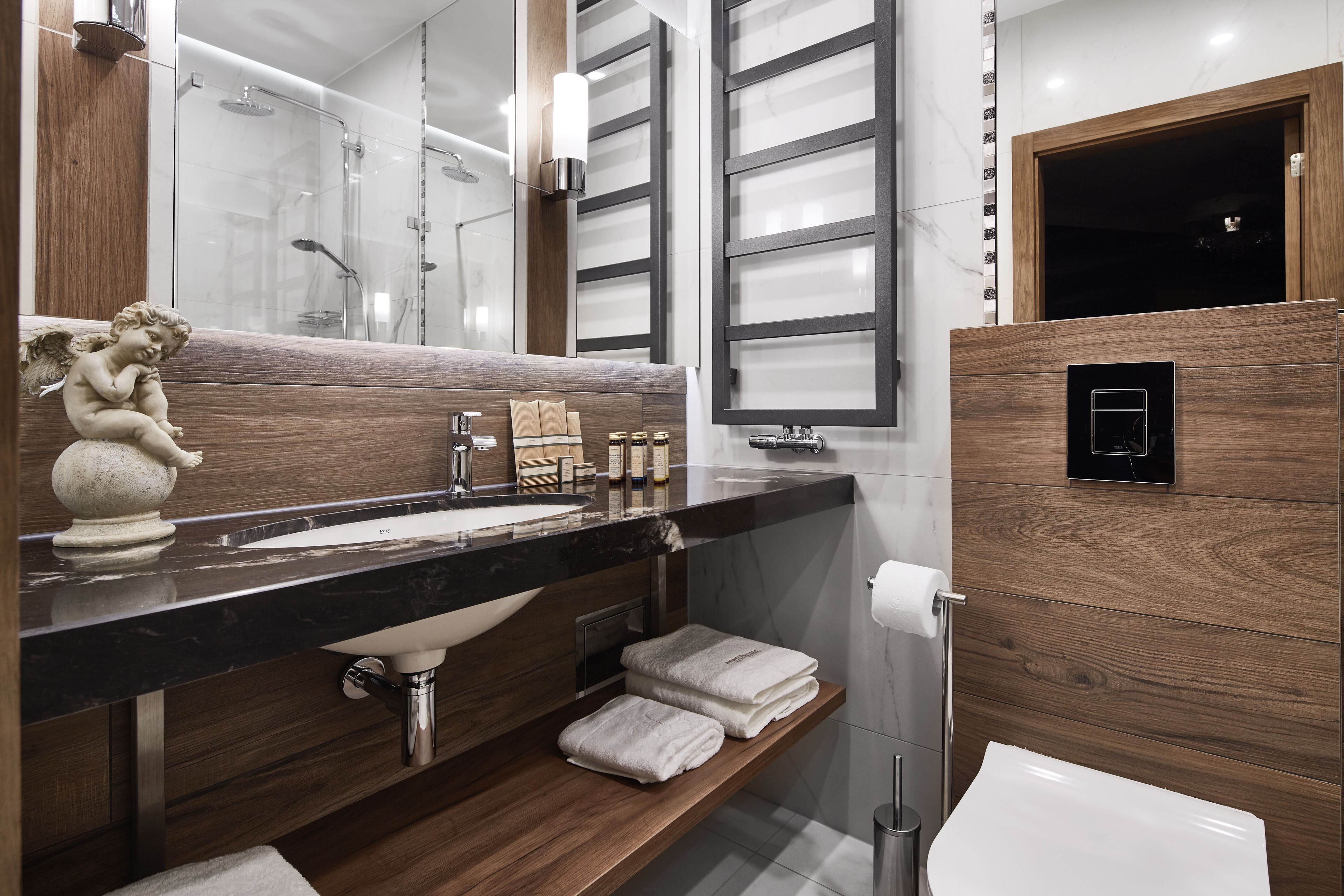 Ein modernes Badezimmer mit einem Holzkosmetikschrank, einem großen Spiegel, einer Duschkabine und einer Toilette.