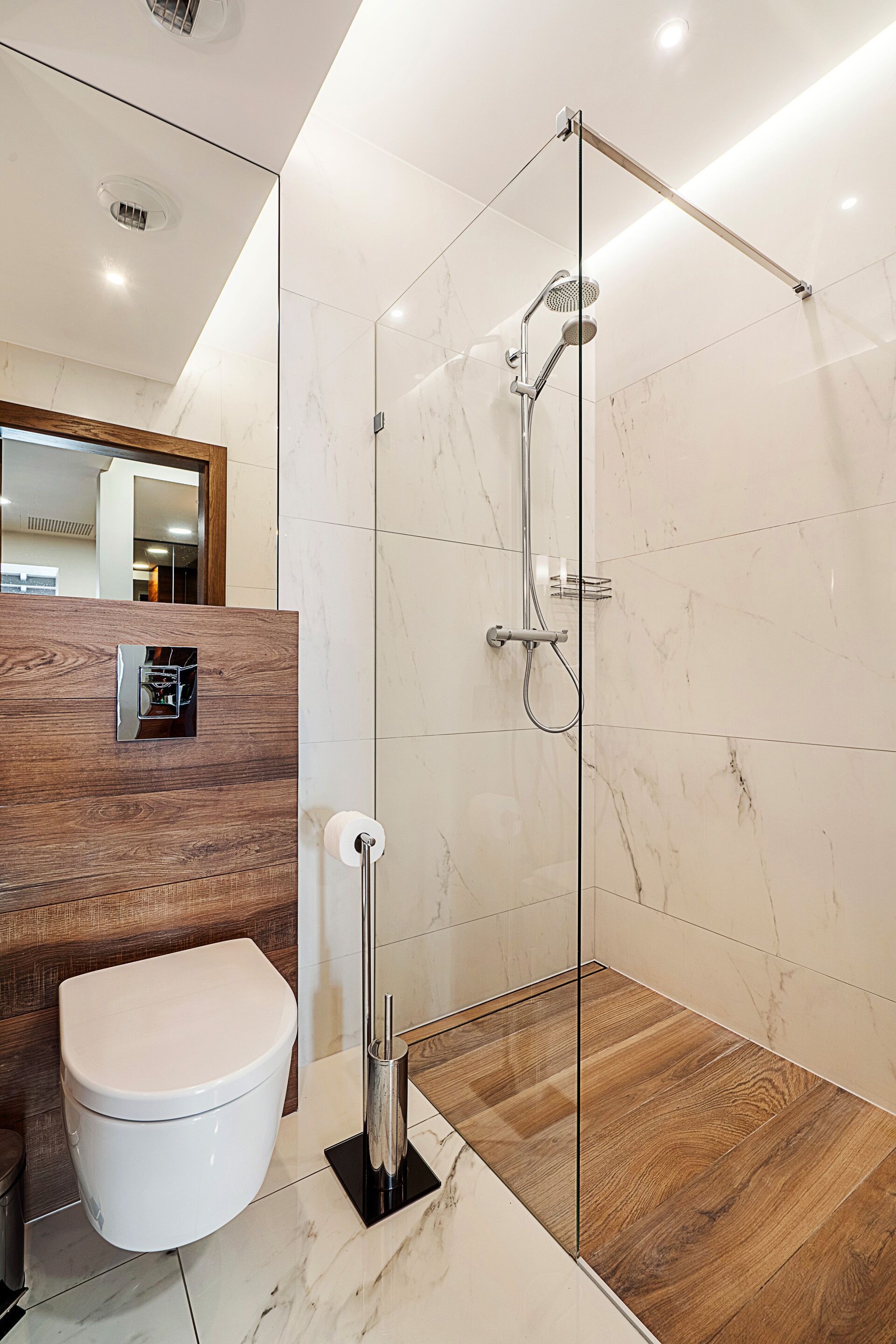 A modern bathroom with a glass-enclosed shower, a wooden vanity, and a white toilet.