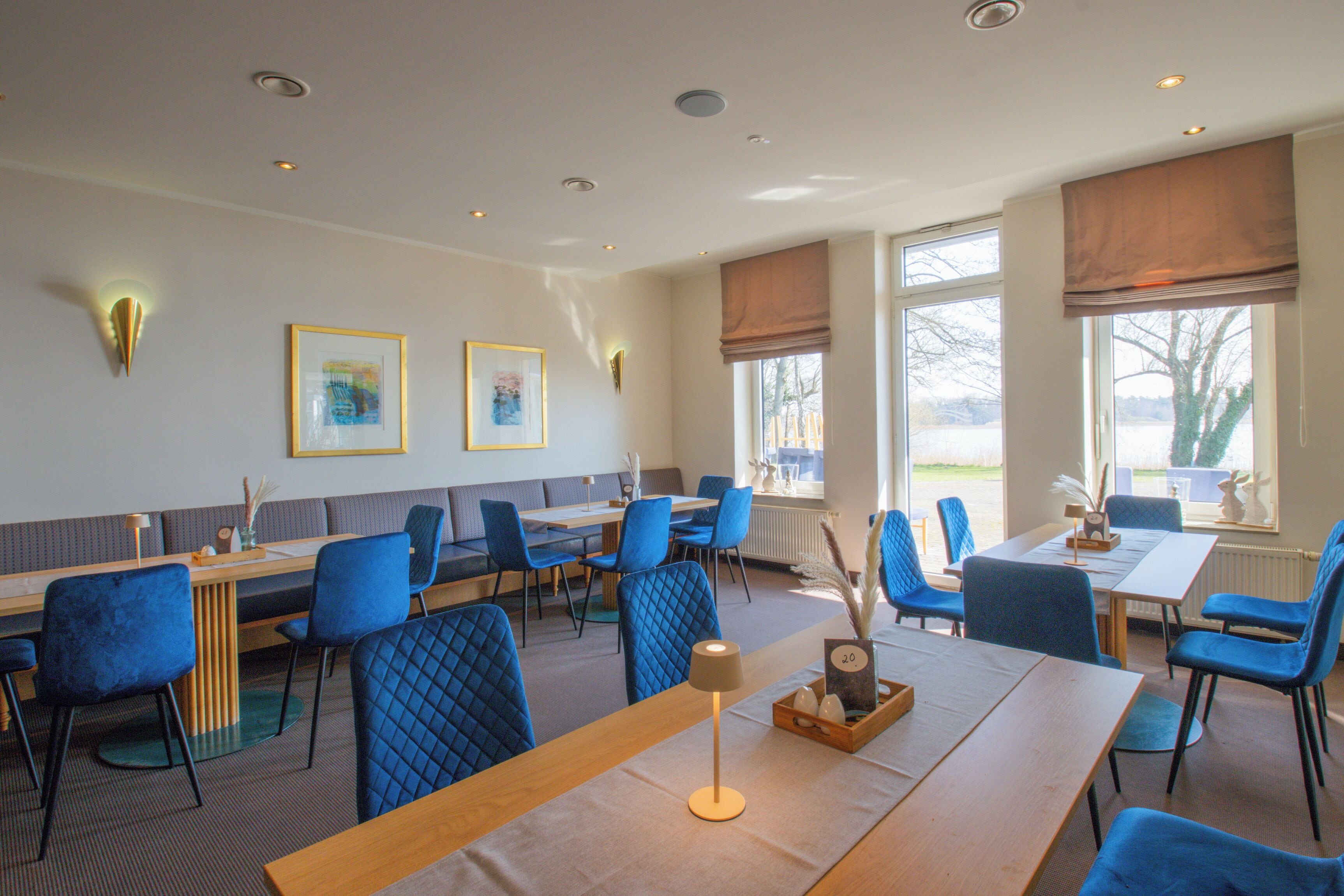 Un restaurant avec des chaises à revêtement bleu, une table en bois et des œuvres d’art encadrées accrochées au mur.