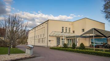 A modern building with a glass entrance, paved walkway, and a stone planter.
