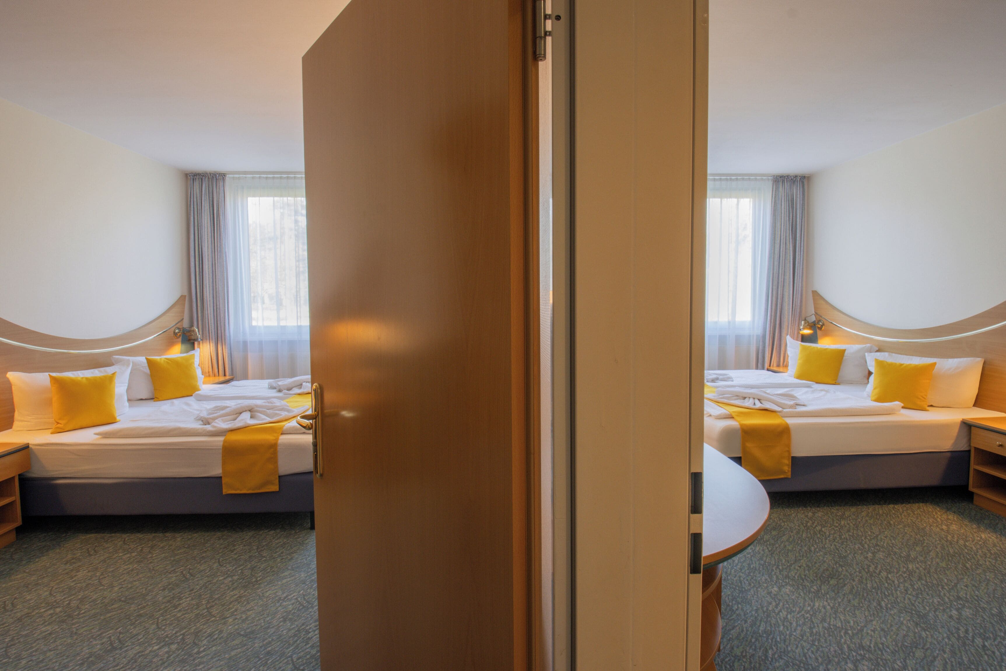A hotel room with a bed, bedside tables, a chair, and a window with curtains.