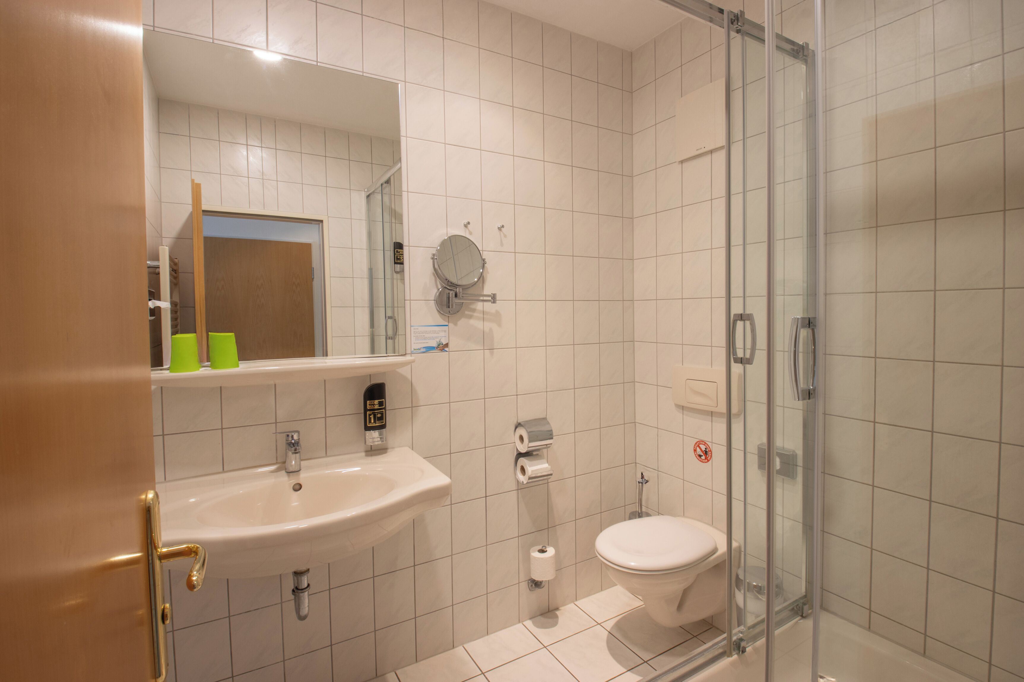 Un baño con lavamanos, inodoro y cabina de ducha con mampara de vidrio.