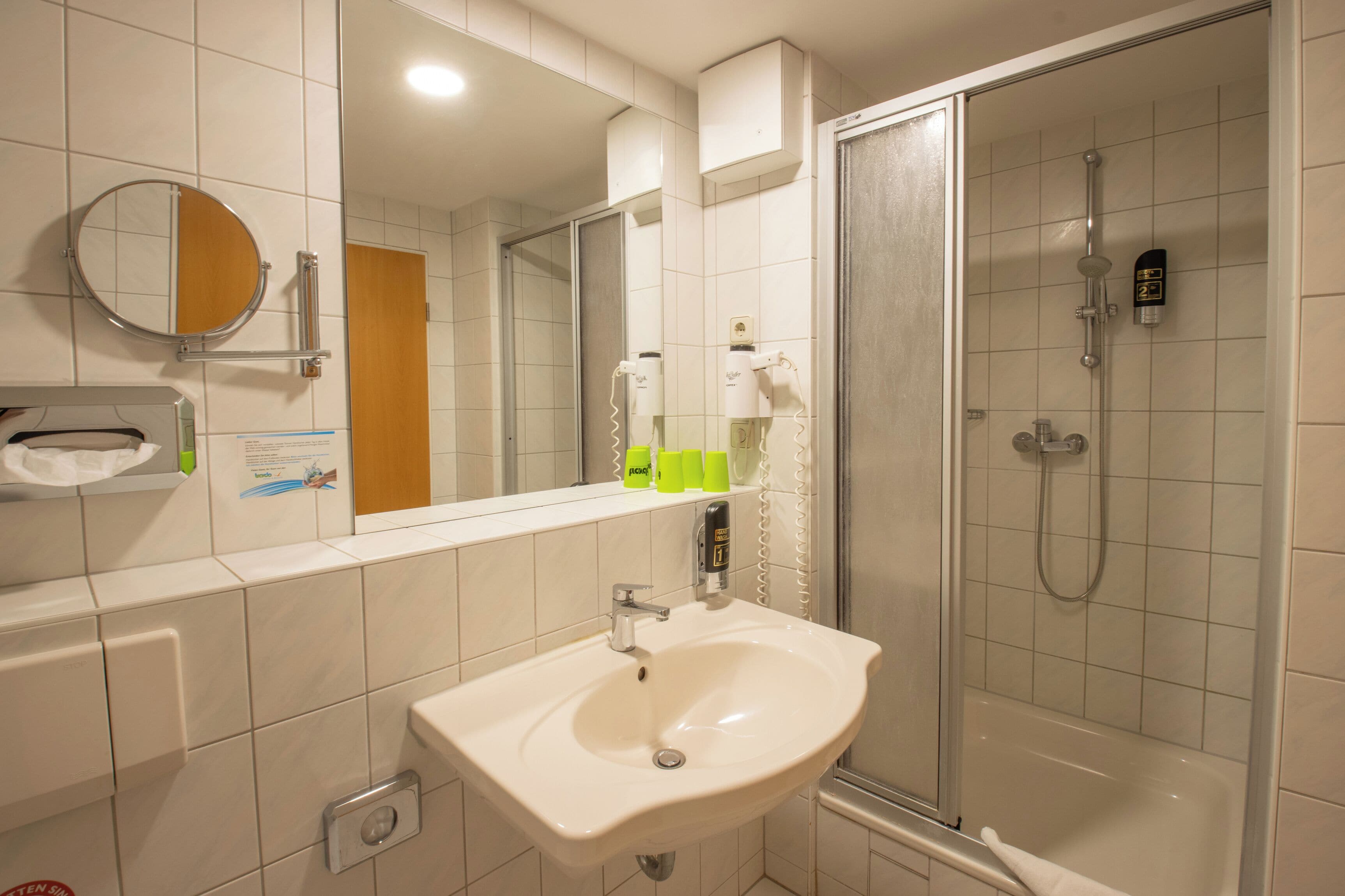 A bathroom with a sink, mirror, and shower.