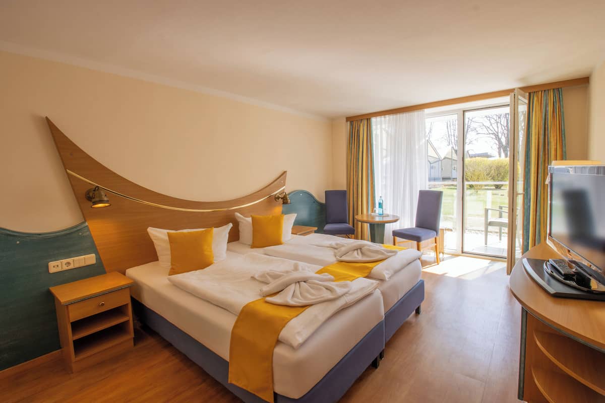 A hotel room with a large bed, a desk with a television, and a view of the outdoors.